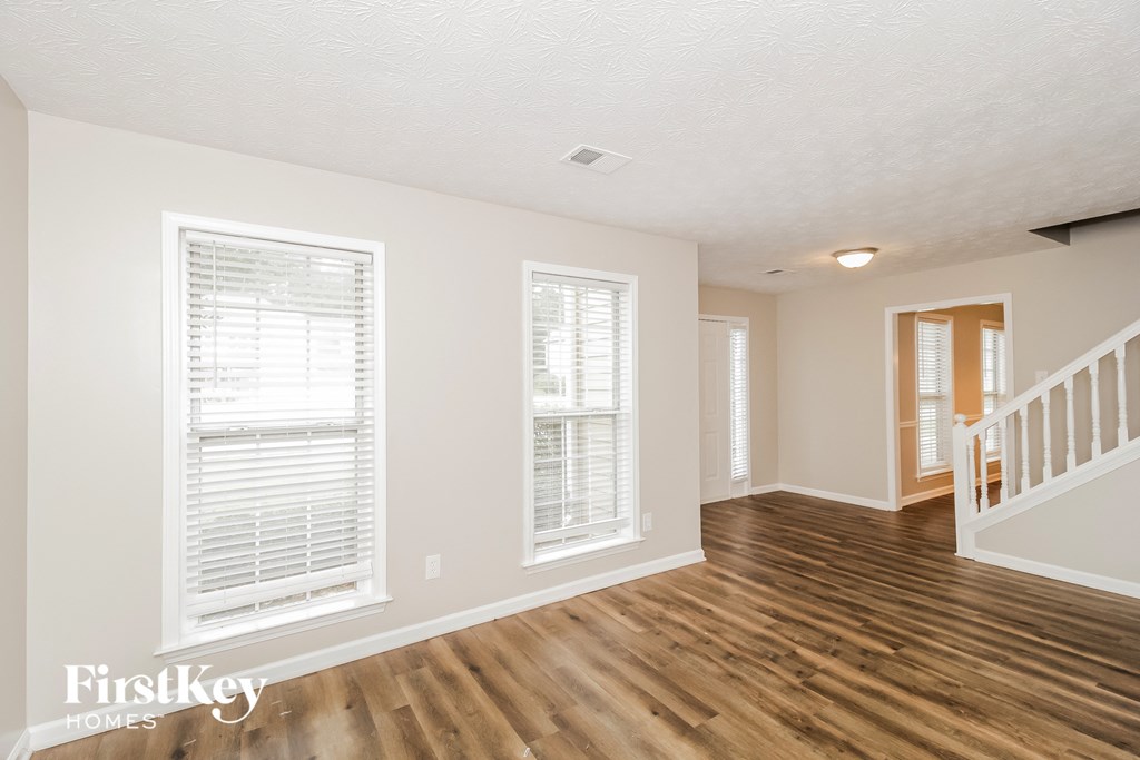 the living room and dining room with wood floors and white walls