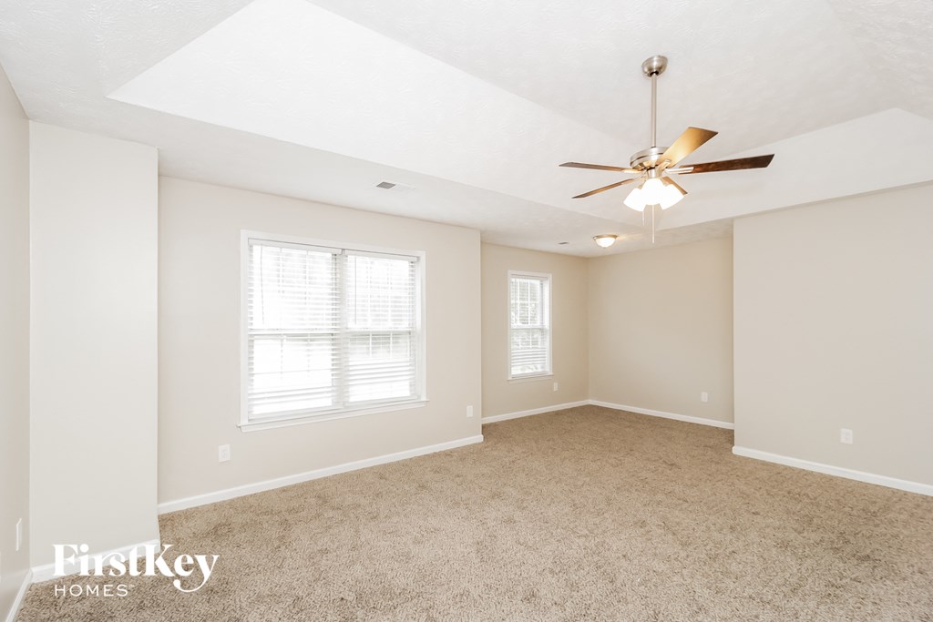 a spacious living room with carpet and a ceiling fan