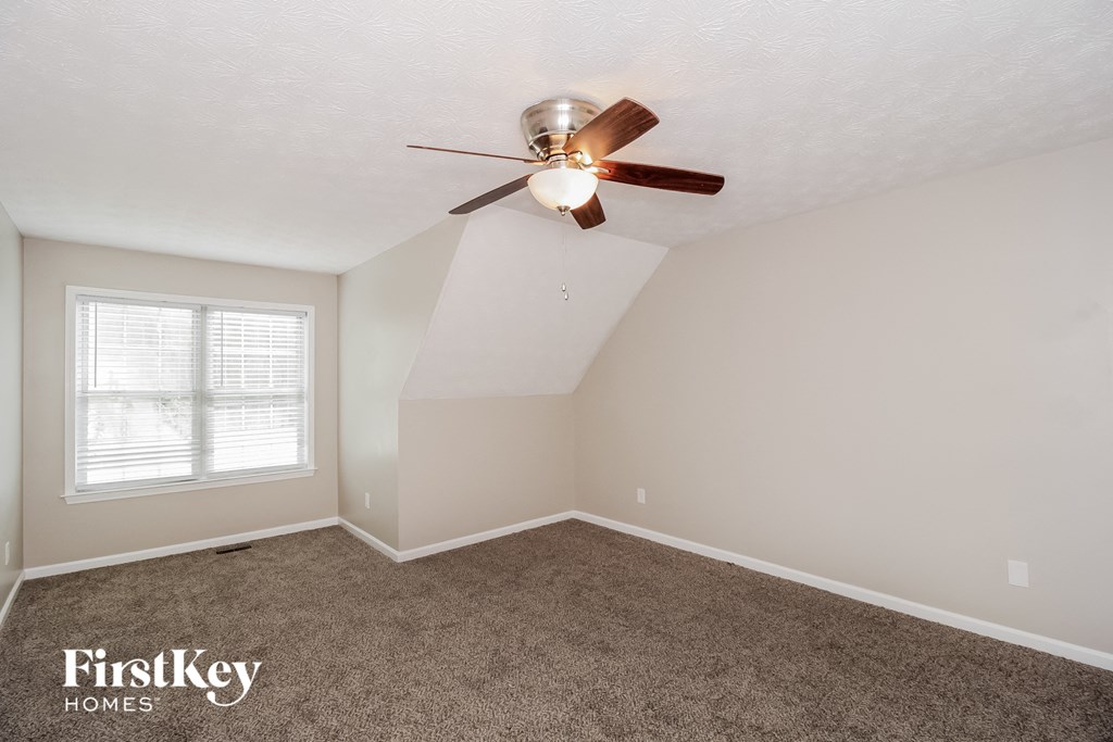 a bedroom with a ceiling fan and a carpet