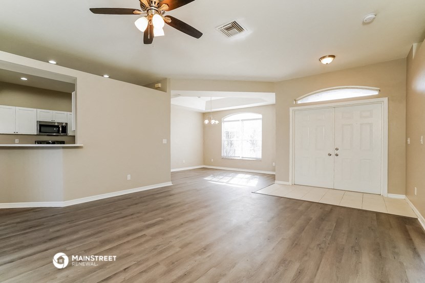 an empty living room and kitchen with a ceiling fan