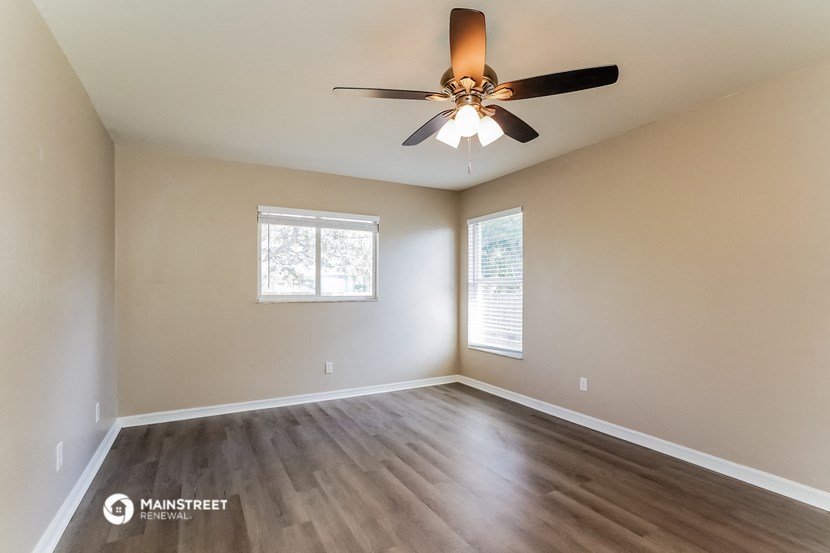 an empty living room with a ceiling fan and a window