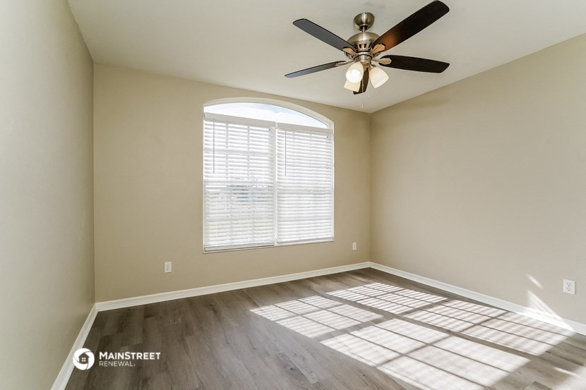 an empty living room with a ceiling fan and a window