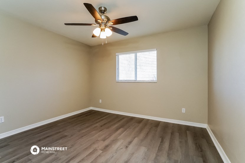 the spacious living room with hardwood floors and a ceiling fan