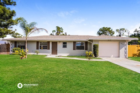 a white house with a lawn and a palm tree