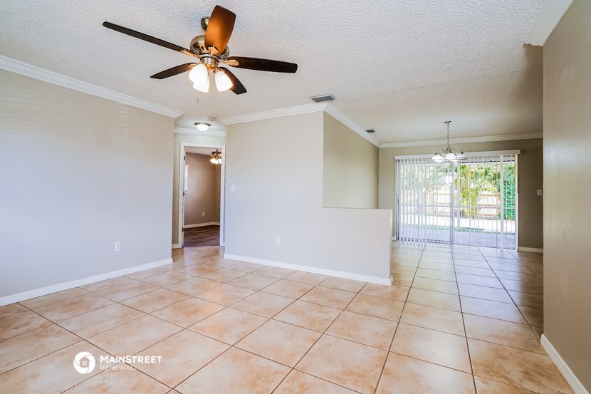 the living room and dining room with a ceiling fan and tile flooring