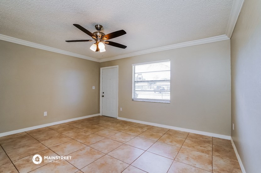 an empty living room with a ceiling fan and a window