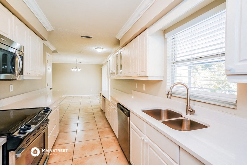 a kitchen with white cabinets and a sink and a window