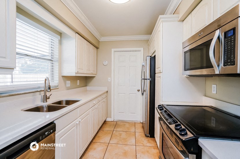 a kitchen with white cabinets and a sink and a refrigerator