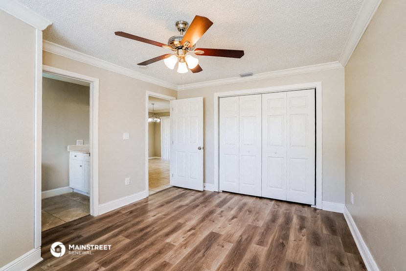an empty living room with a ceiling fan and a closet