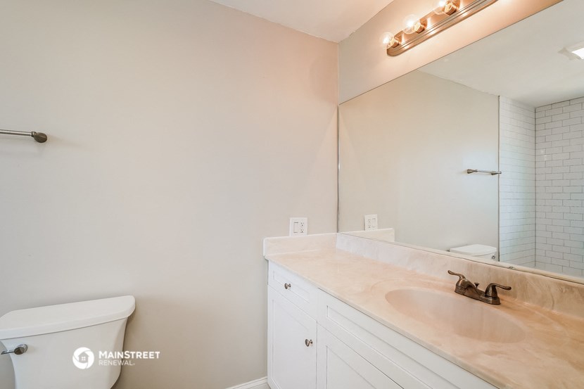 a bathroom with a large mirror and a sink and a toilet