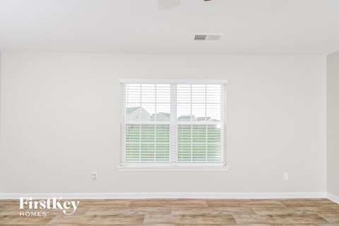 the living room of a home with white walls and a window