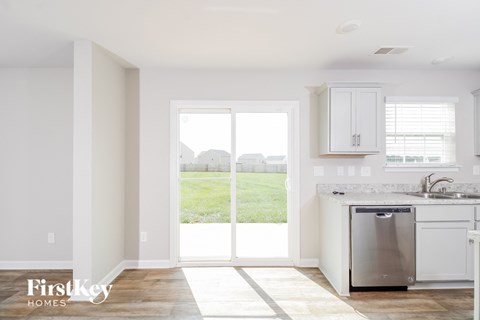 a kitchen with white cabinets and stainless steel appliances and a backdoor to a yard