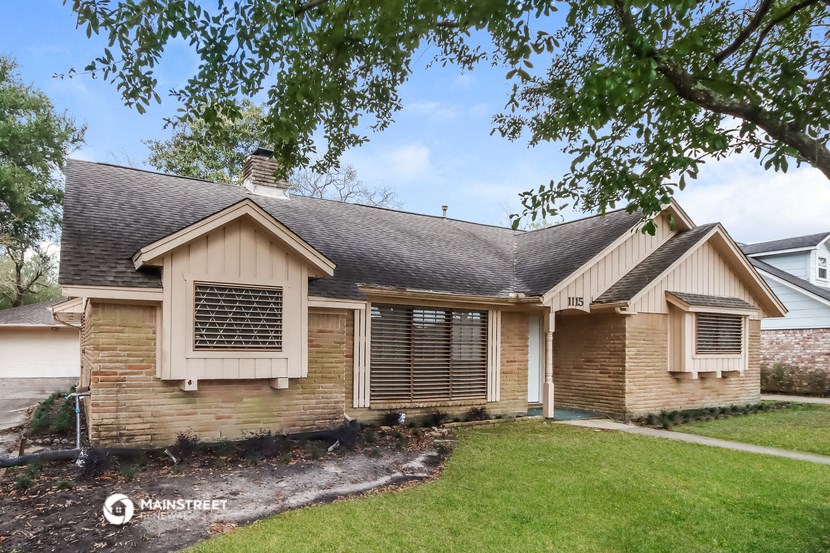 the front of a brick house with a yard and a tree
