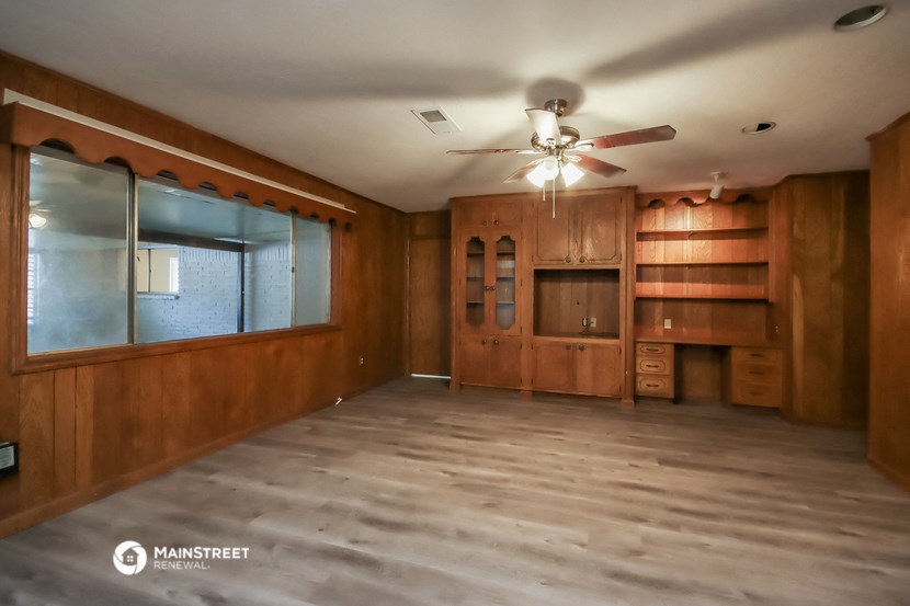 an empty living room with wood paneling and a ceiling fan