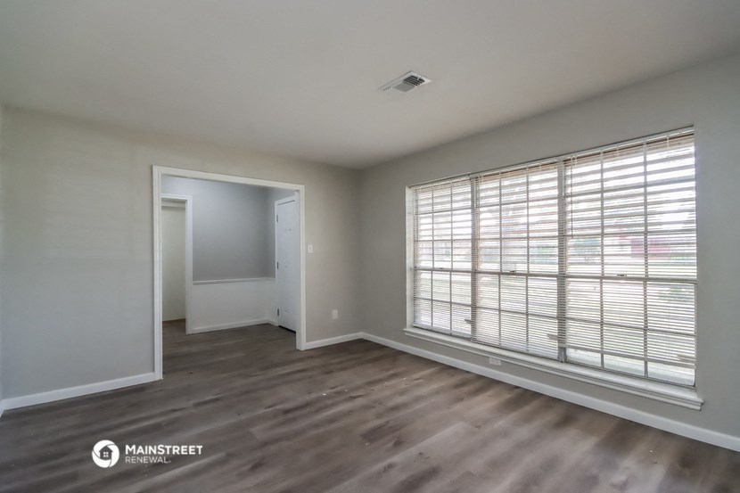 an empty living room with a large window and wood flooring