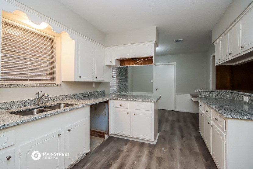a kitchen with white cabinets and granite counter tops