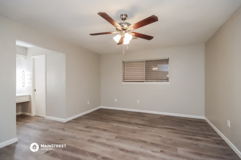 an empty living room with a ceiling fan
