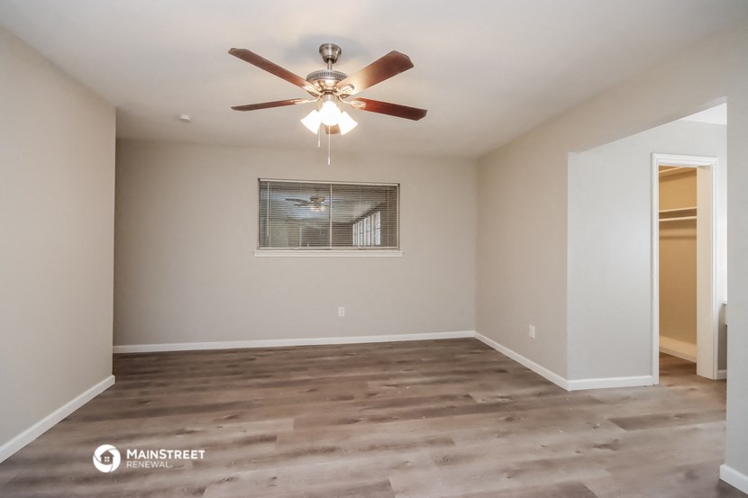 the spacious living room with a ceiling fan