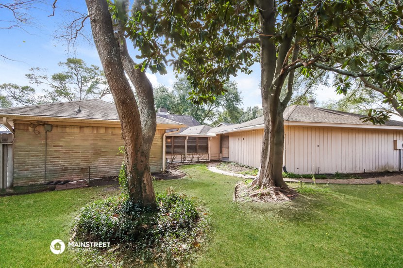 a backyard with two trees and a fence