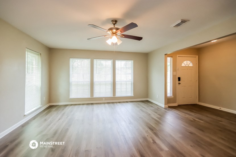 an empty living room with wood floors and a ceiling fan