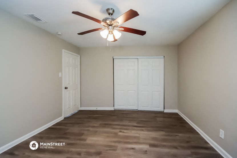 a empty room with a ceiling fan and white doors