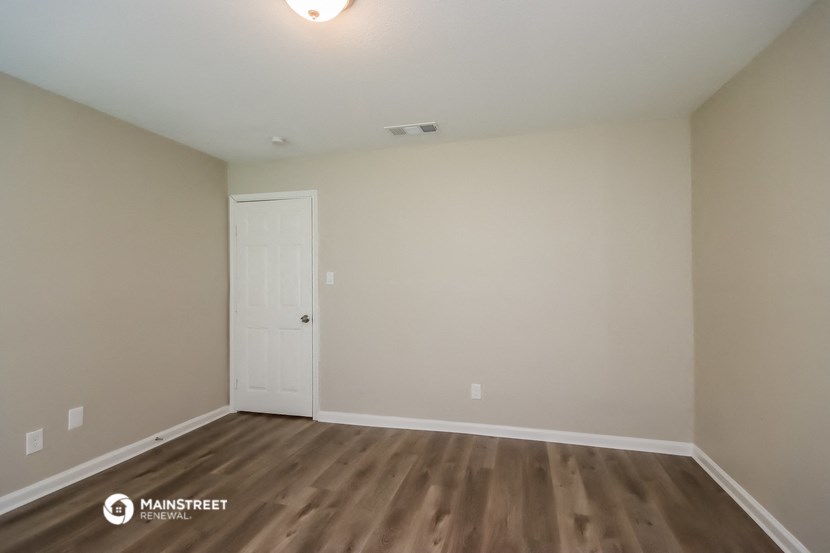 the living room of an apartment with wooden floors and a white door