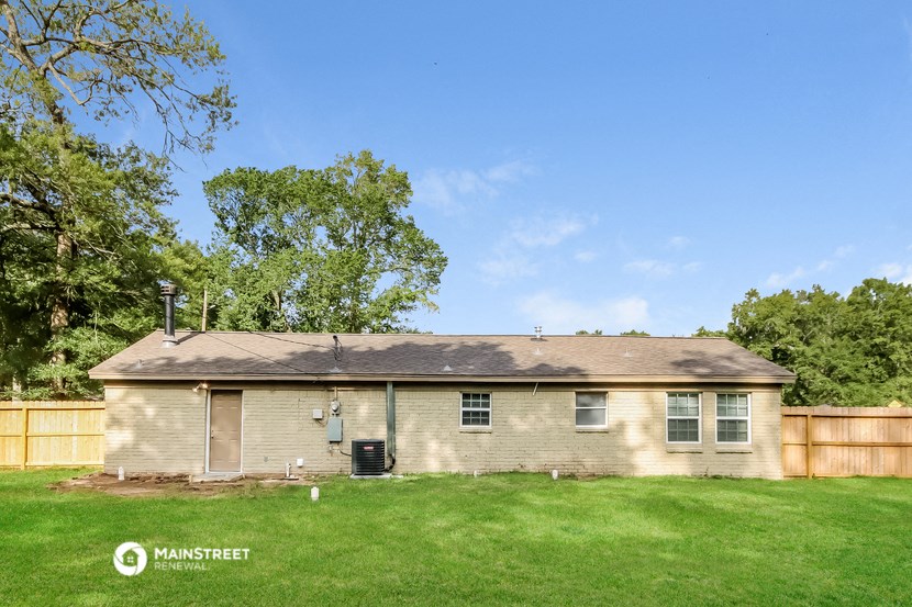 a small brick house with a grassy yard and a fence