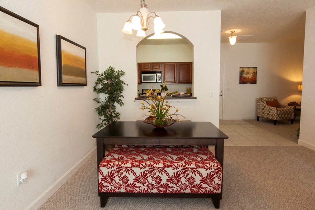 the view of the living room from the dining room with the kitchen in the background