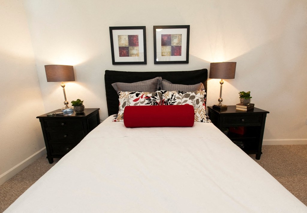 a bedroom with a white bed and two nightstands and two lamps