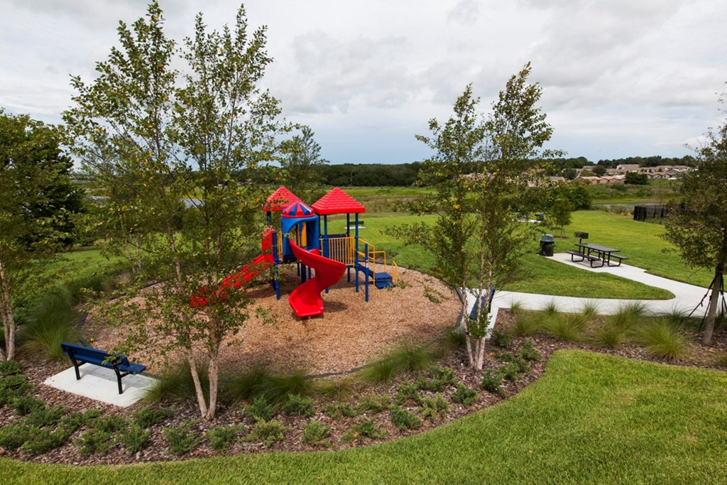 a playground in a park with trees and a bench
