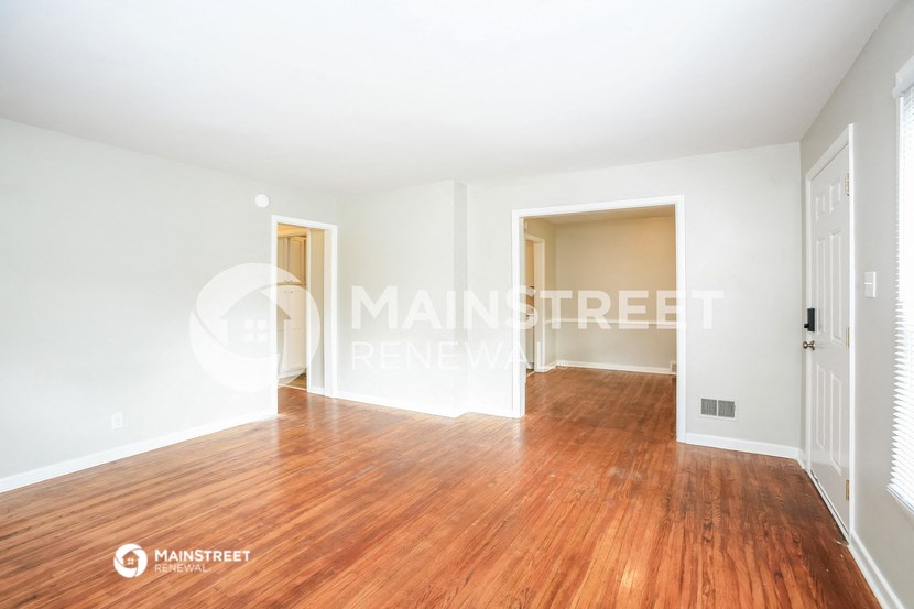 a living room with hardwood floors and a door to a hallway