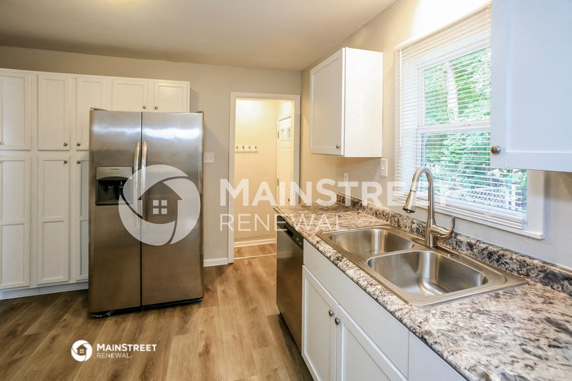 a renovated kitchen with granite counter tops and stainless steel refrigerator