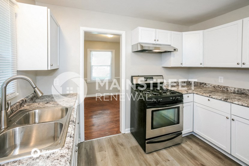 a renovated kitchen with white cabinets and stainless steel appliances