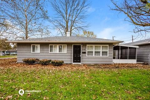 a small gray house with a black door and a yard
