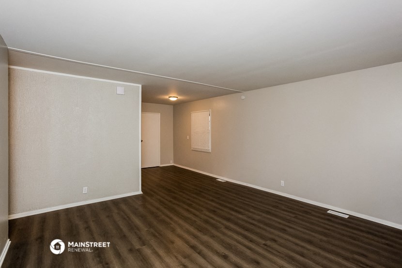 the interior of an empty living room with wood flooring and white walls