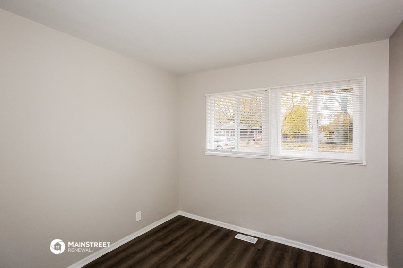 the living room of a house with a window and wooden floors