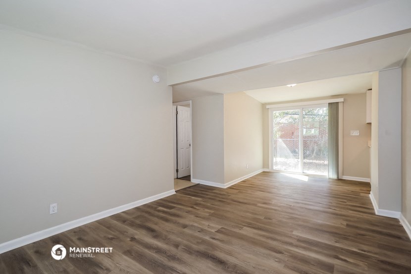 a living room with white walls and wooden floors and a sliding glass door