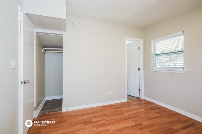 a bedroom with a hardwood floor and a door to a closet