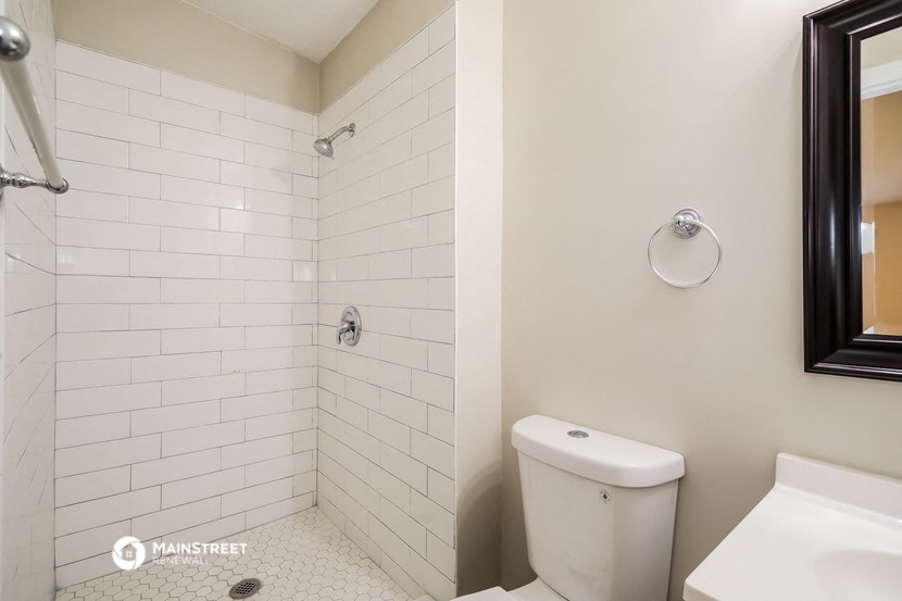 a bathroom with white tiles and a shower and a toilet