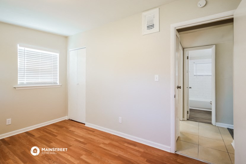 a bedroom with wood flooring and a door to a hallway