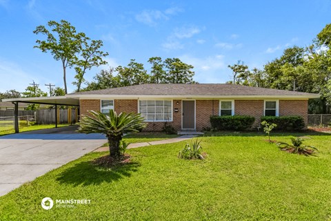 a brick house with a palm tree in front of a driveway