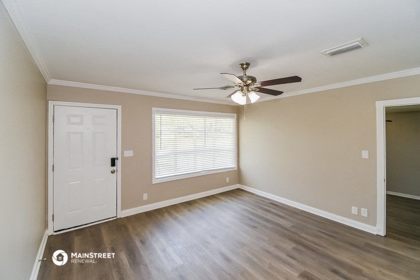 an empty living room with a ceiling fan and a door