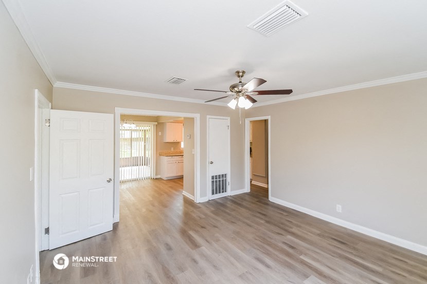 the living room and dining room of an empty house with a ceiling fan
