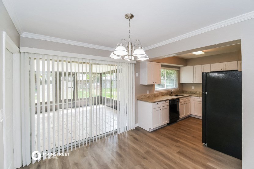 a kitchen and living room with a large window with white blinds
