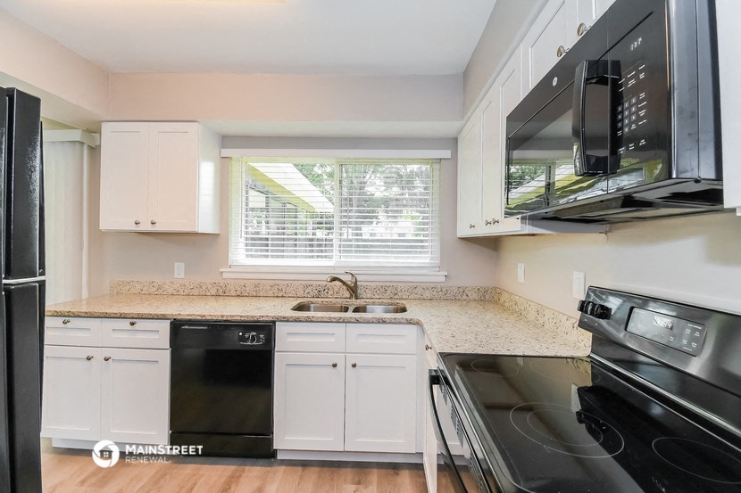 a kitchen with black appliances and white cabinets