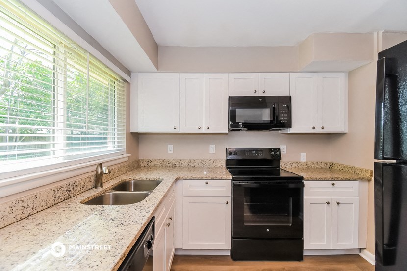 a kitchen with white cabinets and granite counter tops and black appliances