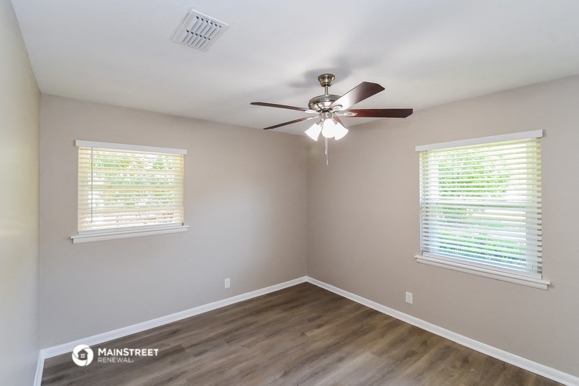 an empty room with a ceiling fan and two windows