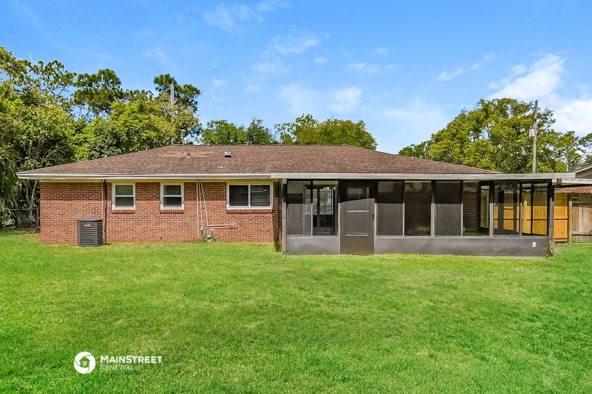 a small brick house with a porch and a grass yard