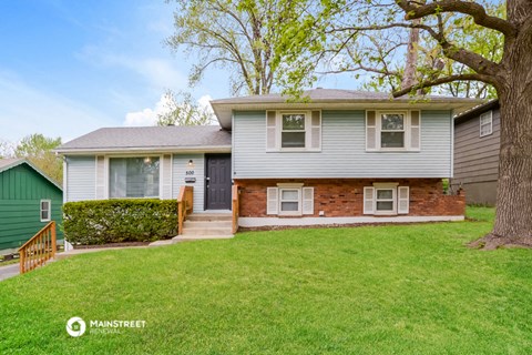 a blue house with a green lawn and a tree
