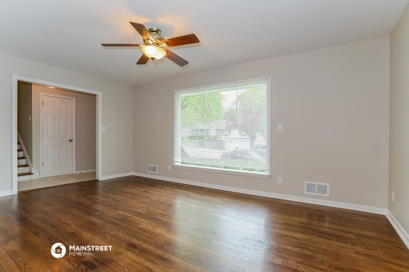 the living room of an empty house with a ceiling fan
